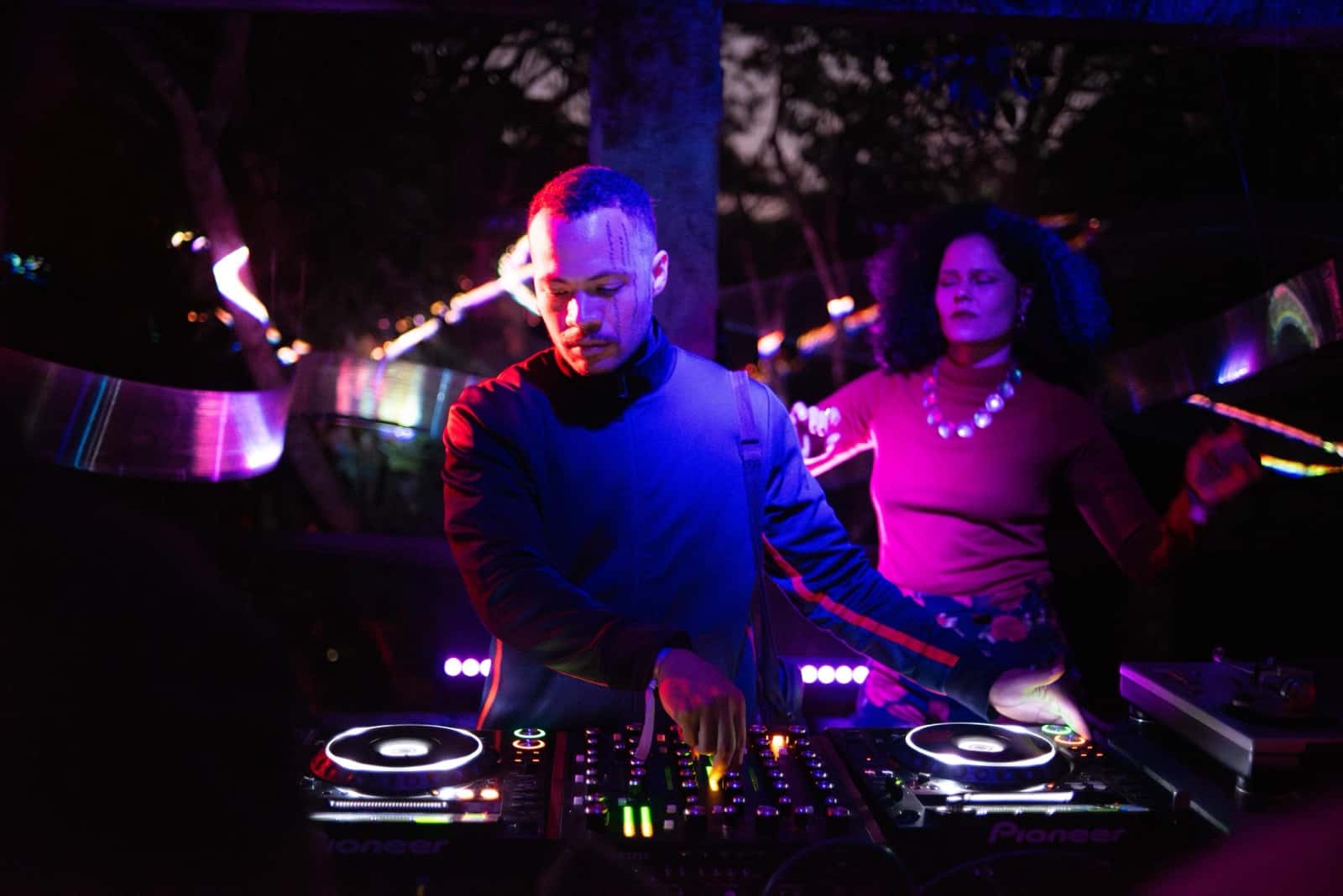 DJs nas pick-ups sob a luz roxa da noite